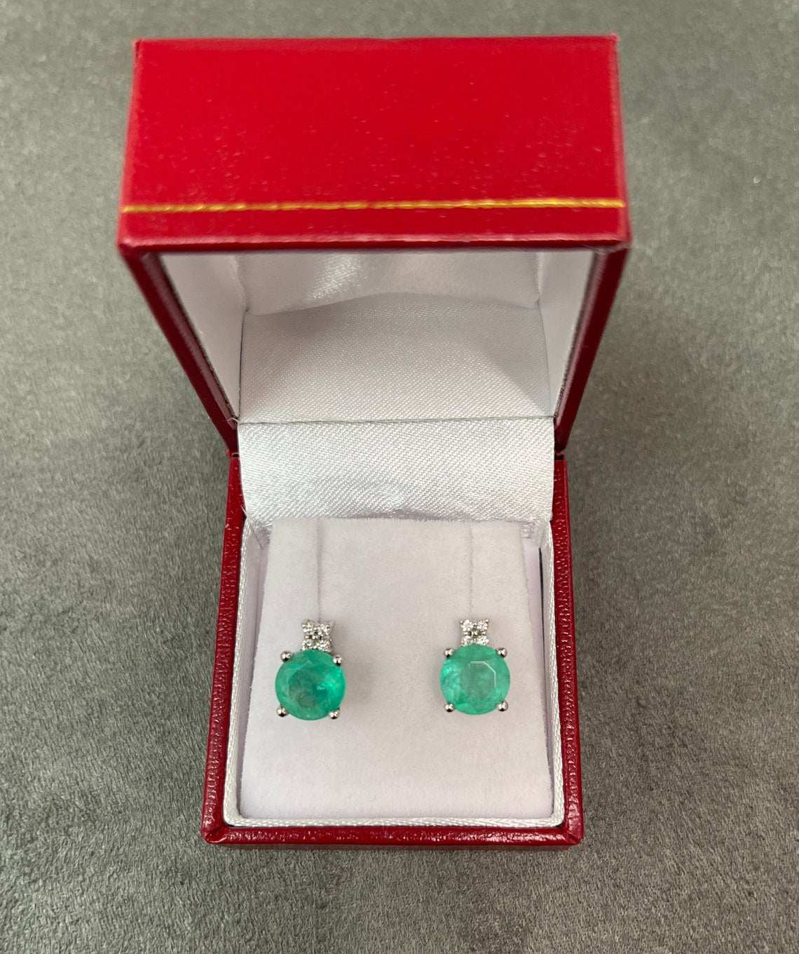14K gold Colombian emerald and diamond stud earrings featuring rich blue-green round stones and stacked design.