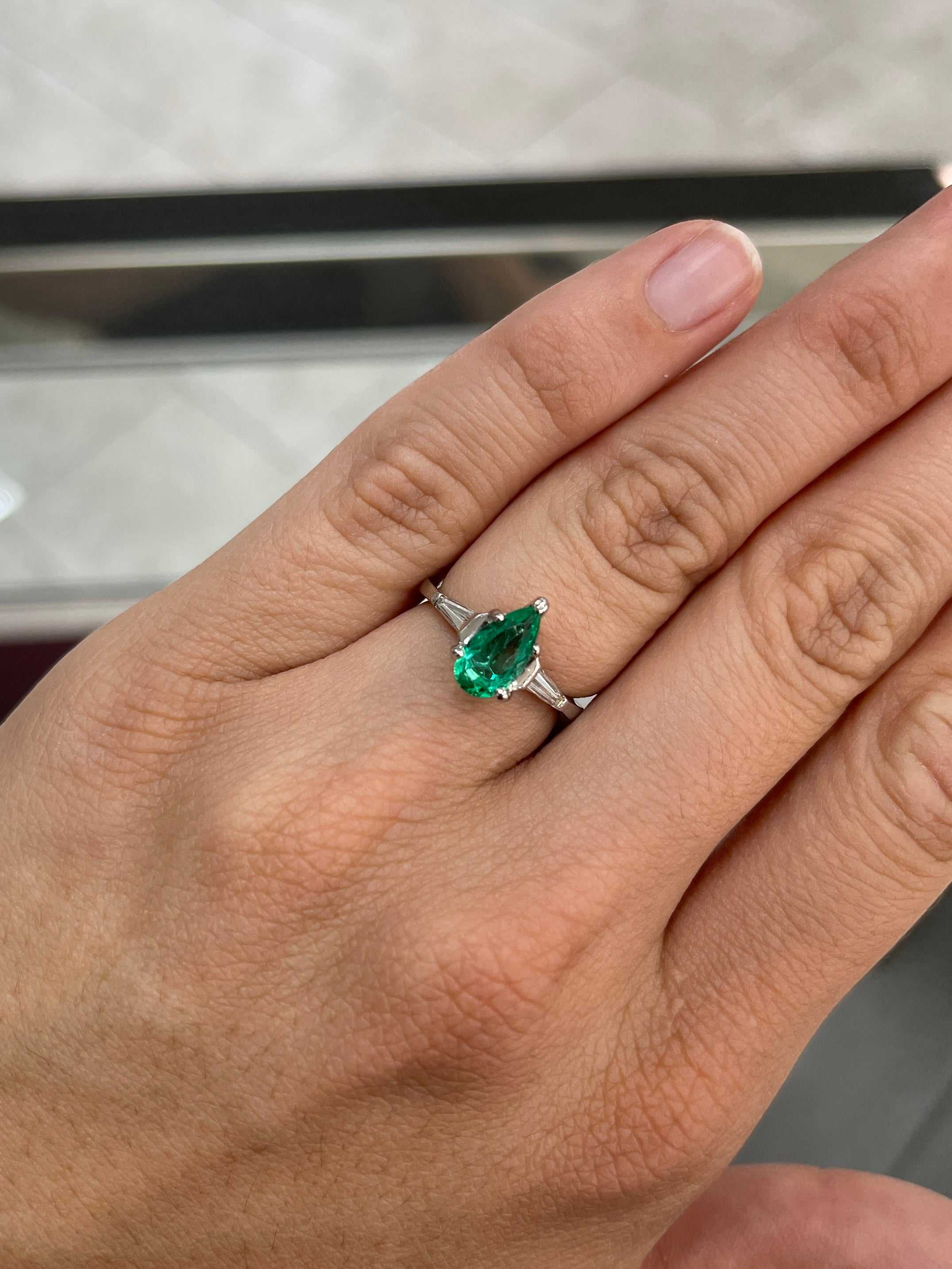 Elegant engagement ring featuring a 1.49tcw pear cut Colombian emerald with tapered baguette diamonds in 18K gold.