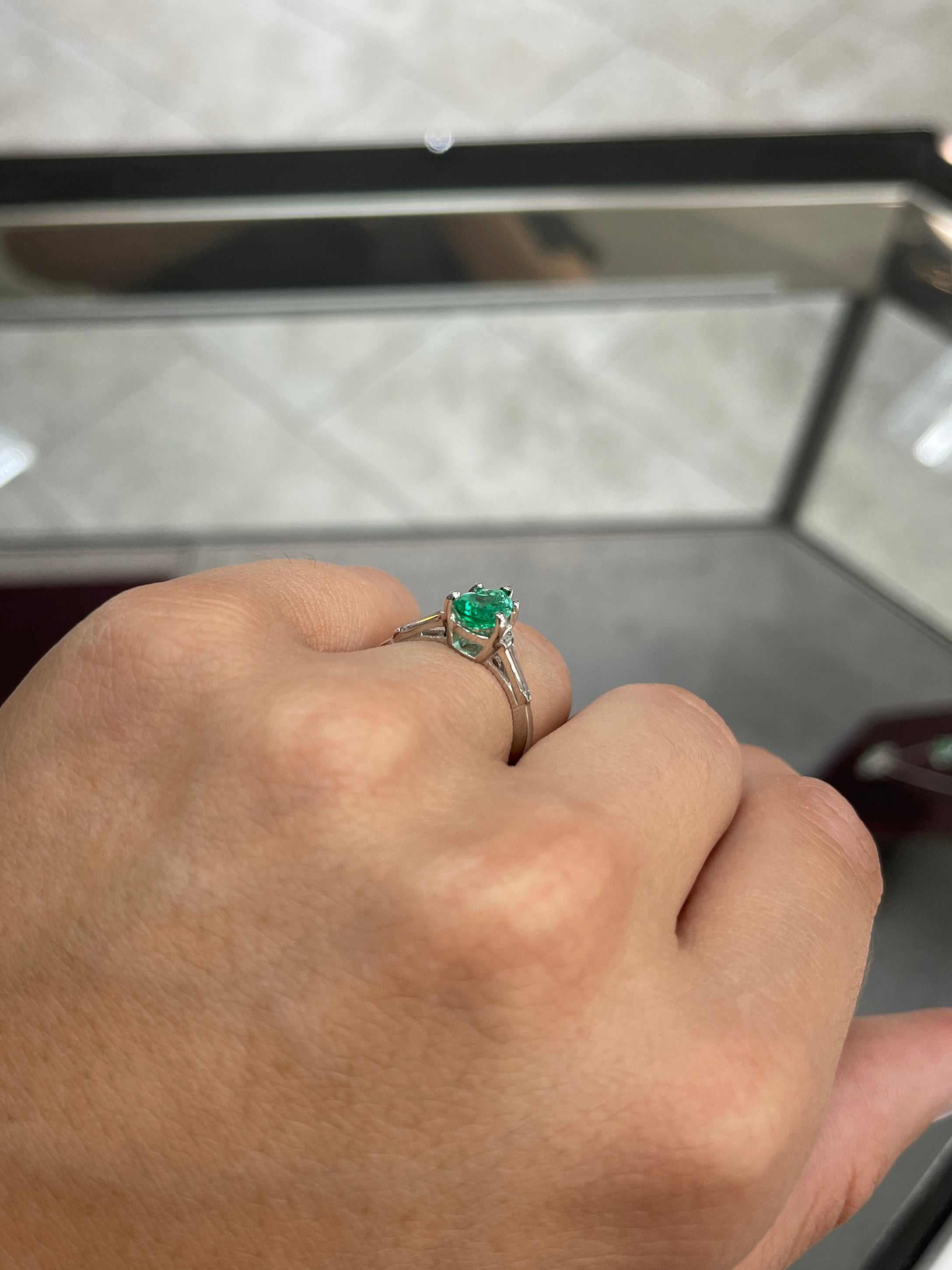 Elegant engagement ring featuring a 1.49tcw pear-cut Colombian emerald and tapered baguette diamonds in 18K gold.