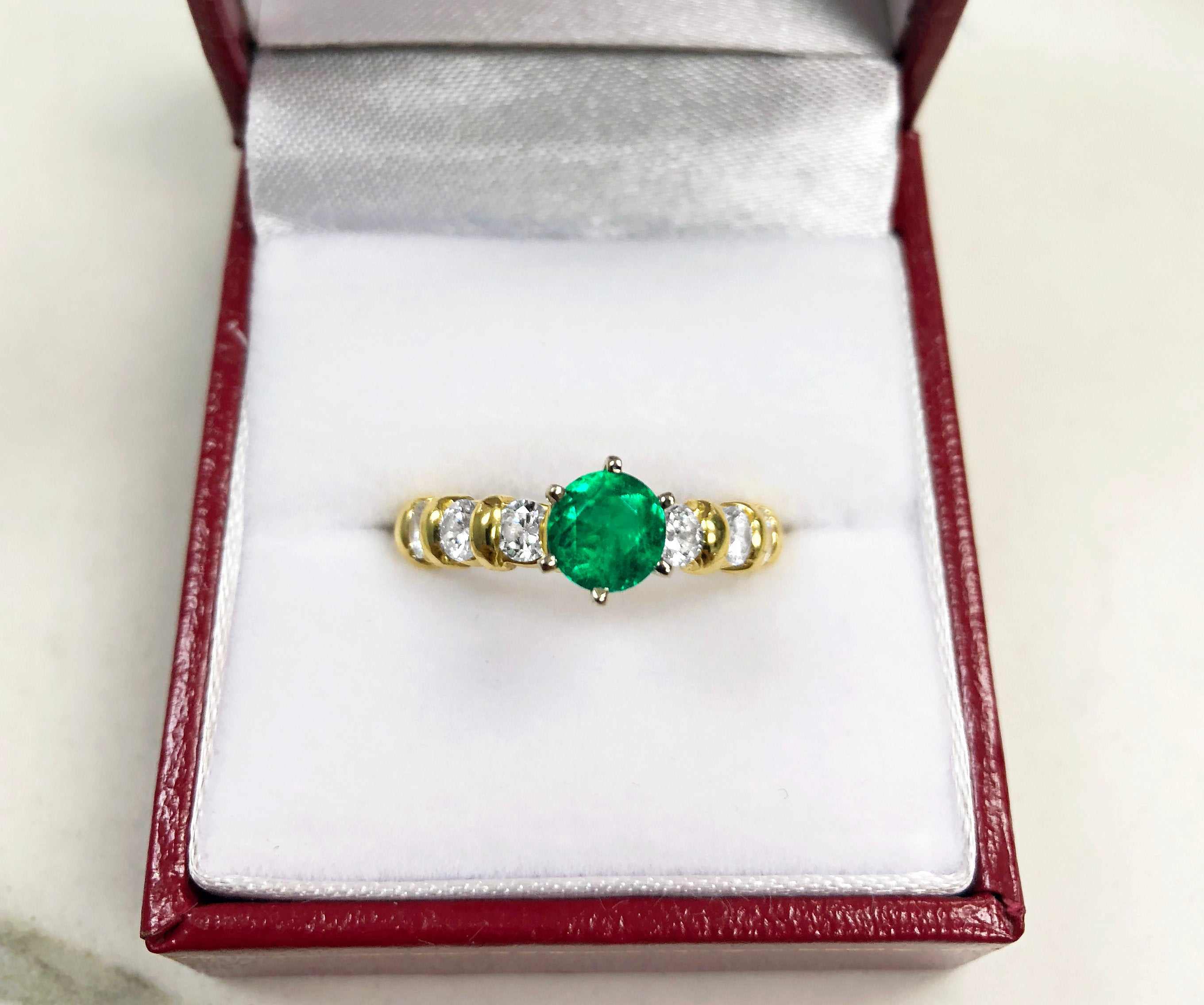 JR Colombian Emeralds engagement ring featuring a 1.69tcw round emerald with diamond accents in 18K yellow gold.