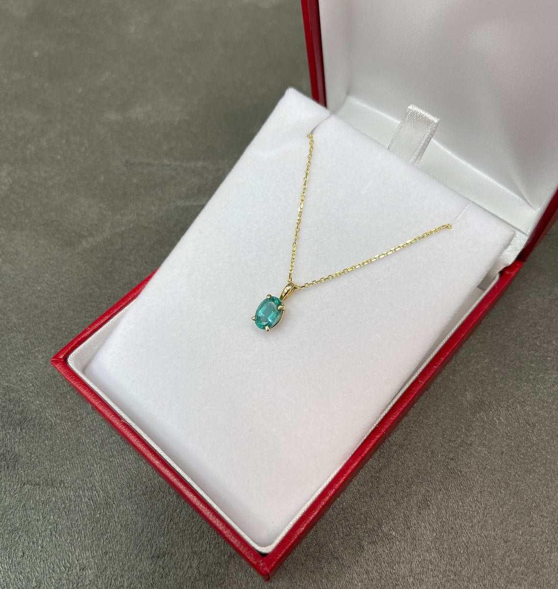 Natural bluish green 1.15 carat oval cut emerald solitaire pendant in 14K gold, from JR Colombian Emeralds, shown with a chain.